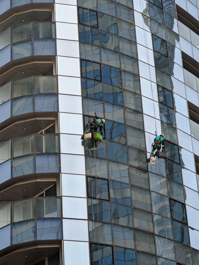our-story Professional window cleaners working on a skyscraper in Abu Dhabi, showcasing urban architecture.